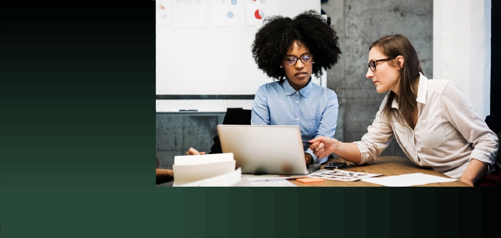 Two women going over a project on a laptop during a business meeting.