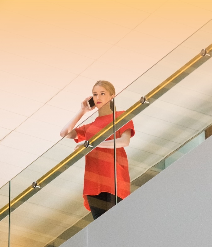Woman speaks on a phone while standing on an office balcony