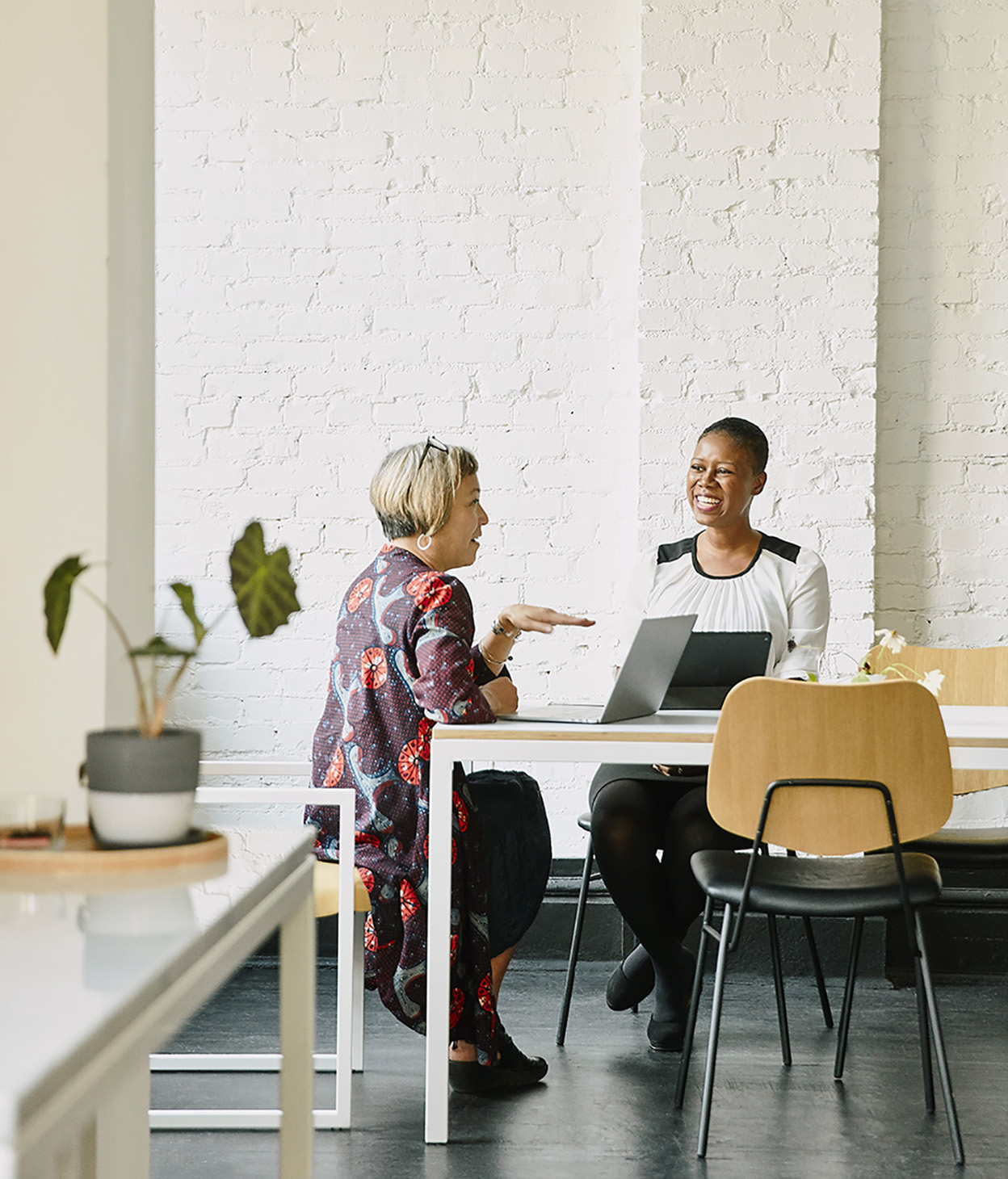 two people on their laptops meeting at a table